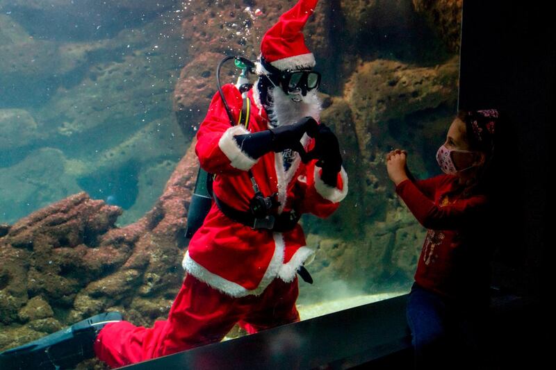 Dressed as Santa Claus, a diver makes the heart symbol to a young girl at the Creta Aquarium in the city of Heraklion on the Greek southern island of Crete, December 15. AFP