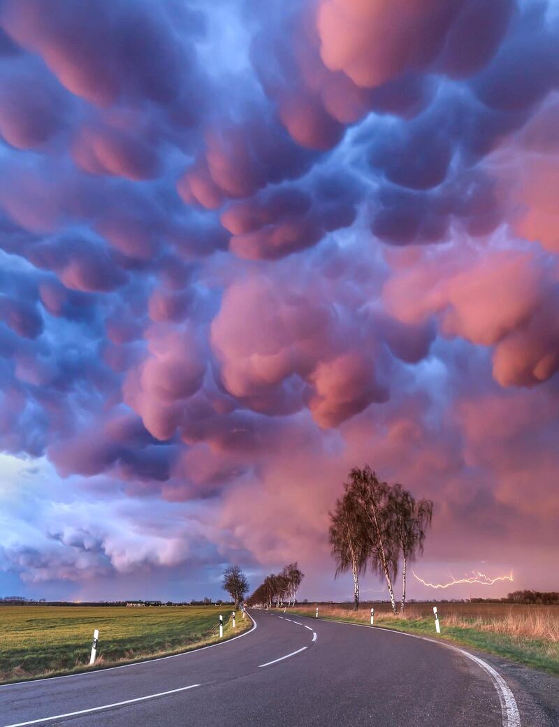 'Mammatus Outbreak', Boris Jordan: 'This was by far the most spectacular mammatus display I've ever seen in my entire life. After a line of thunderstorms passed by and the sun disappeared behind the horizon, low-hanging mammatus clouds began to shine red and blue. At this moment I was just speechless, as the sky really looked like not from this planet. And as a nice bonus, distant lightning made the composition perfect. Mammatus mostly appear in association with strong thunderstorms, if the sinking air, which contains high amount of liquid water or ice, is cooler than the surrounding air.'