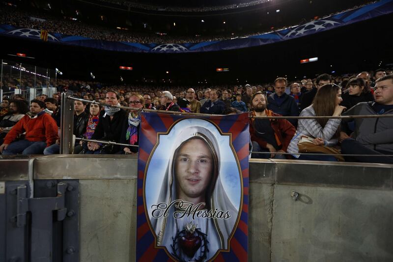 Supporters sit in the stands behind a poster depicting Barcelona's Argentinian forward Lionel Messi as the Messiah during the UEFA Champions League semi-final second leg football match FC Barcelona vs FC Bayern Munich at the Camp Nou stadium in Barcelona on May 1, 2013.  AFP PHOTO / QUIQUE GARCIA
 *** Local Caption ***  029682-01-08.jpg