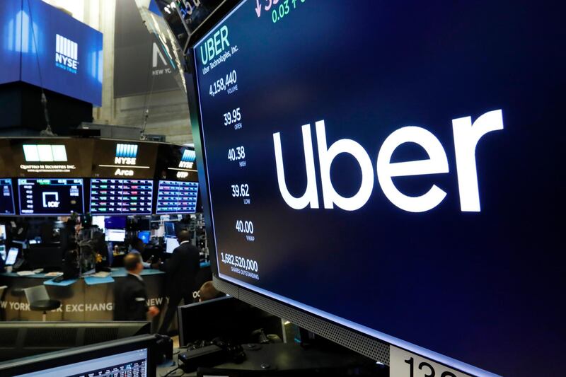 FILE - The logo for Uber appears above a trading post on the floor of the New York Stock Exchange, Thursday, May 30, 2019. Uber has reported that it whittled its losses at the end of a topsy-turvy year. In 2020, the ride-hailing service was forced to rely more heavily on its food-delivery service. That's because the pandemic dramatically reduced the number of people willing to hop into a car driven by a stranger. The fourth-quarter results announced Wednesday, Feb. 10, 2021 drew a picture of a company making strides in its attempt to recover from a staggering blow delivered last March. (AP Photo/Richard Drew, file)