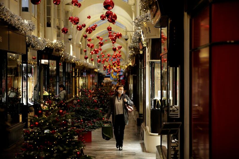 A woman walks past Christmas trees and decorations in Burlington Arcade, where all non-essential shops are temporarily closed, in London. AP Photo