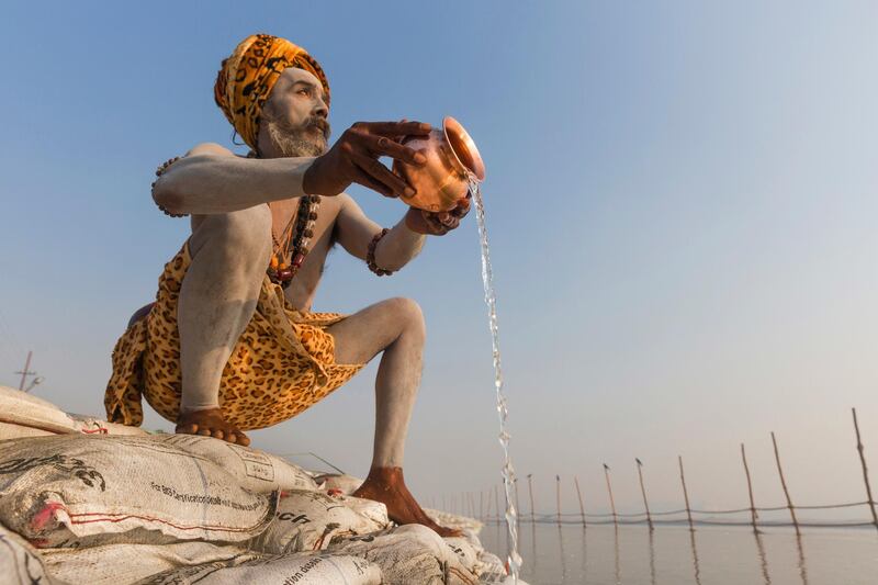 Sadhu, or a Hindu holy man, offers prayers to the Sun God after taking a ritualistic dip at the "Sangam," the meeting point of Indian holy rivers the Ganges and the Yamuna, during the annual traditional fair of Magh Mela in Allahabad, India. Rajesh Kumar Singh / AFP Photo