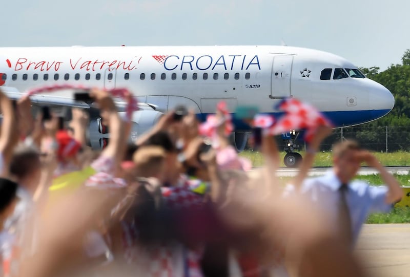 People cheer as the Croatian national football team lands on the tarmac of the international airport in Zagreb. Attila Kisbenedek / AFP