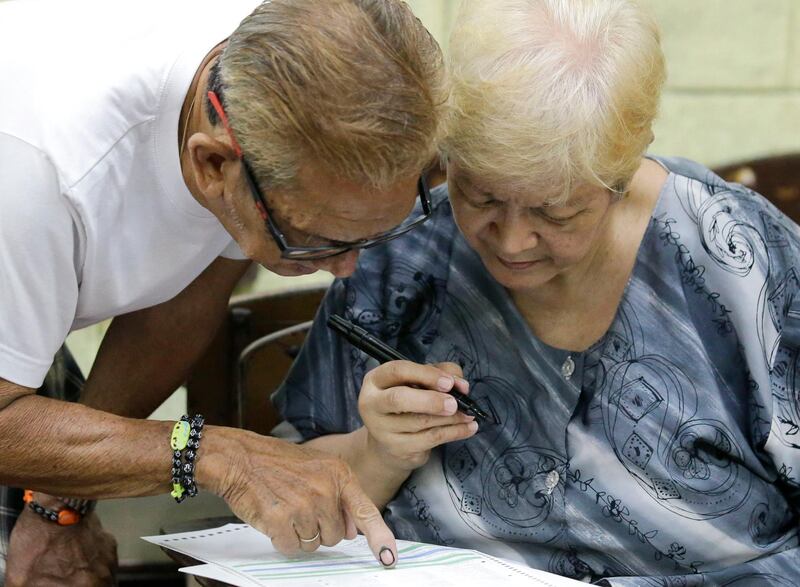 A man helps his wife fill out her ballot. AP Photo