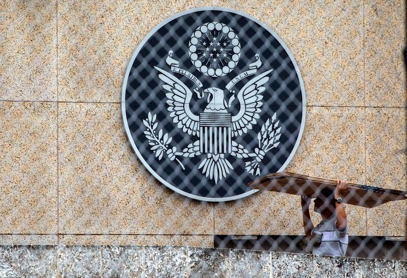 In this Sept. 29, 2017 photo, a worker carries cardboard inside the compound of the United States embassy in Havana, Cuba, Friday, Sept. 29, 2017.   The United States expelled 15 of Cuba's diplomats Tuesday to protest its failure to protect Americans from unexplained attacks in Havana, plunging diplomatic ties between the countries to levels unseen in years.  (AP Photo/Desmond Boylan)