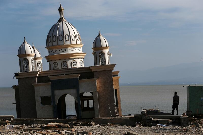A police officer stands next to the remains of a mosque destroyed by the earthquake and tsunami in Palu. Reuters