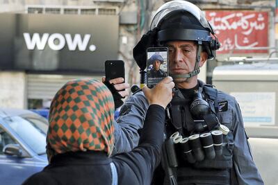 A Palestinian woman takes a picture of a member of the Israeli security forces as he takes her picture in a street in Jerusalem on December 16, 2017, as demonstrations continue to flare in the Middle East and elsewhere over the US president's declaration of Jerusalem as Israel's capital. (Photo by AHMAD GHARABLI / AFP)