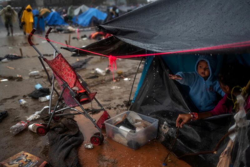 A one-year-old migrant boy from Honduras gestures towards rainwater dripping from his family's tent. Reuters