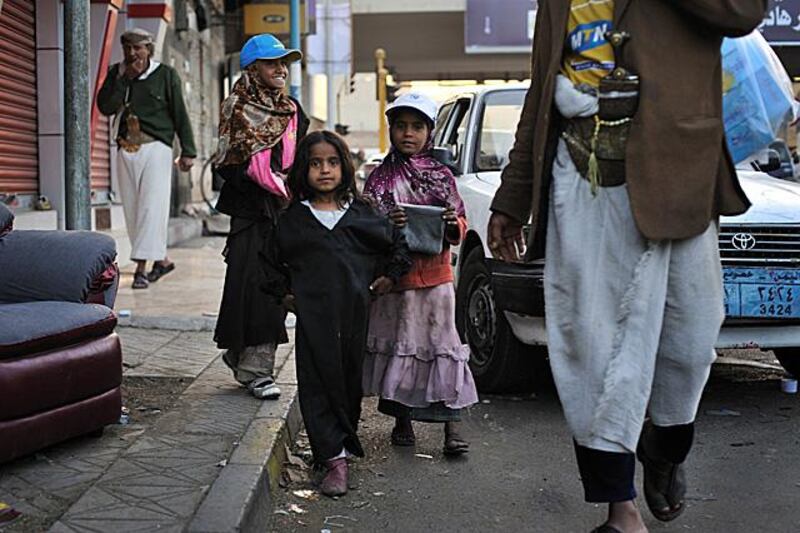 The daughters of the Hajiri family walk home with their father after spending the day selling tissues to passing drivers at an intersection in downtown Sana'a. Photo: Lindsay Mackenzie for the National.