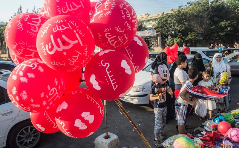 An Egyptian Muslim family buys balloons from a street vendor as they celebrate the first day of Eid al-Adha, or the "Feast of Sacrifice", outside al-Sedik mosque in the northeastern suburb of Sheraton in the capital Cairo, on September 1, 2017. / AFP PHOTO / KHALED DESOUKI