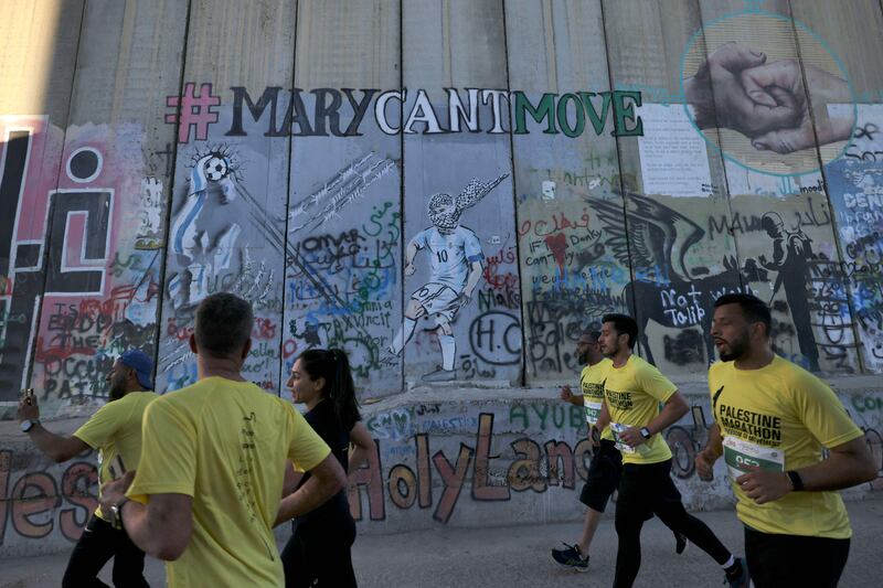 Participants run past a section of Israel's controversial barrier in Bethlehem, in the Israeli-occupied West Bank. AFP