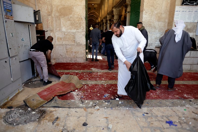 Palestinians clean the entrance to the mosque. Debris and broken glass cover the floor. Reuters