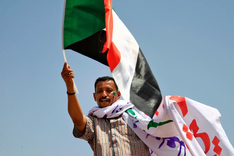 A Sudanese opposition supporter waves a national flag during a sit-in outside the army headquarters in Khartoum on May 5, 2019, as thousands of protesters remain encamped in the area to demand the current 10-member army council that took power after the ouster of the country's former president be replaced by a civilian administration. Sudanese mediators facilitating talks between the army rulers and protest leaders have proposed the country have two transition councils, with one led by generals overseeing security, according to a senior opposition leader and member of the umbrella protest group the Alliance for Freedom and Change. / AFP / ASHRAF SHAZLY
