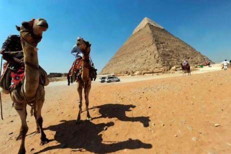 Egyptian men ride their camels as they wait for customers in front of the pyramid of Khafre in Giza, southwest of central Cairo.