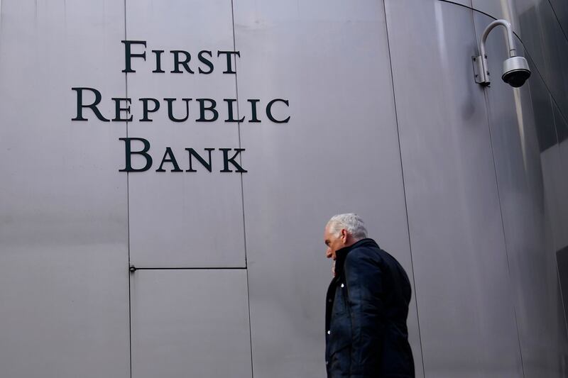 A pedestrian walks past a sign at a First Republic Bank in San Francisco. The troubled lender will be sold to JP Morgan. AP