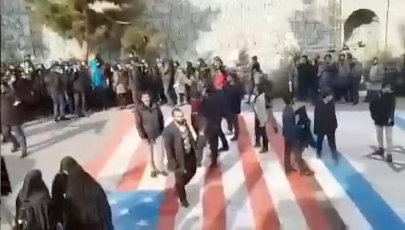 Several people walk on US and Israeli flags while others avoid stepping on the flags by walking around them, at the Shahid Beheshti University in Tehran, Iran.  Reuters