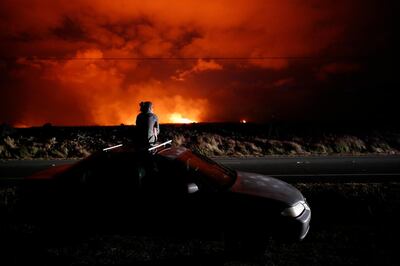 Brittany Kimball watches as lava erupts from from a fissure near Pahoa, Hawaii, Saturday, May 19, 2018. Two fissures that opened up in a rural Hawaii community have merged to produce faster and more fluid lava. Scientists say the characteristics of lava oozing from fissures in the ground has changed significantly as new magma mixes with decades-old stored lava. (AP Photo/Jae C. Hong)