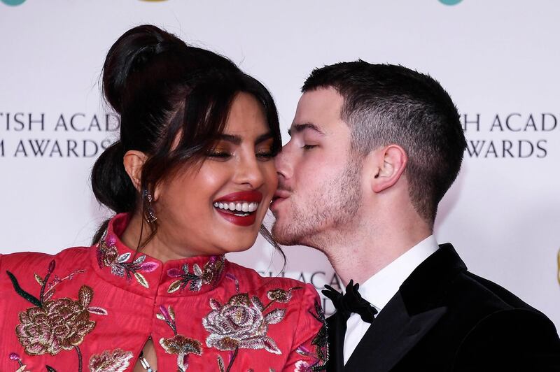 Actress Priyanka Chopra Jonas, left, is kissed by her husband singer Nick Jonas upon arrival at the Bafta Film Awards, in central London, Sunday, April 11 2021. (AP Photo/Alberto Pezzali)