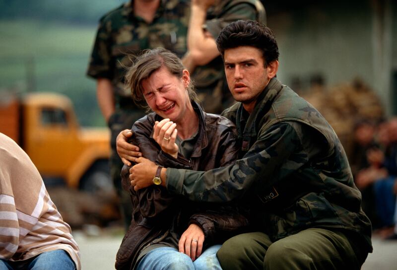 A Croatian man tries to comfort a woman as they and fellow Croats flee their village in Bosnia, in June 1993. Getty Images