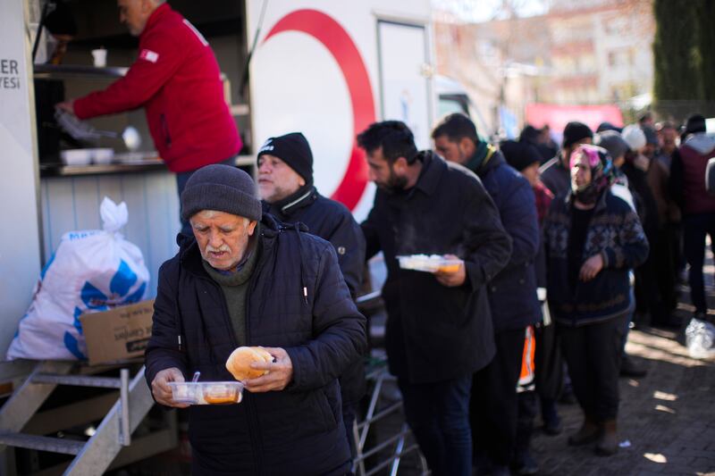 Earthquake survivors receive distributed meals in Golbasi, Turkey. AP