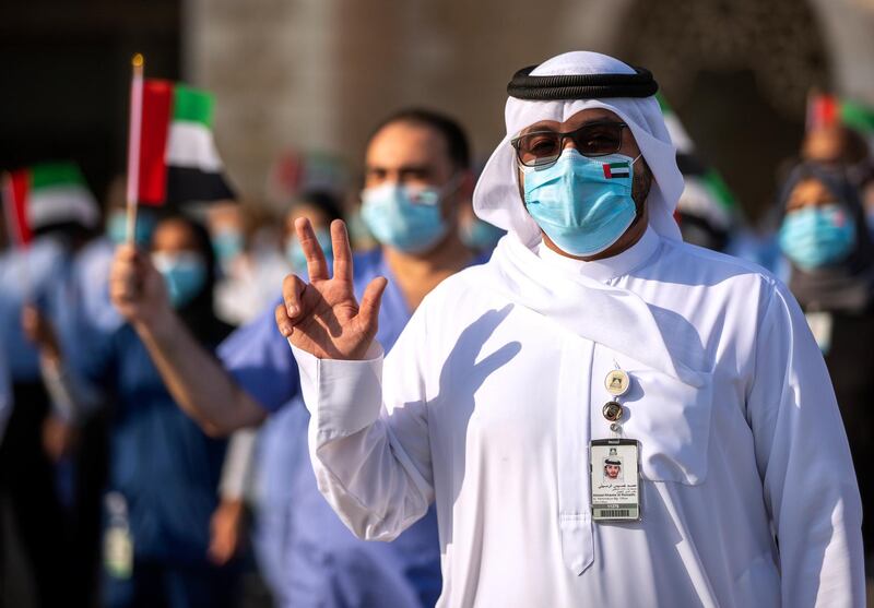 Abu Dhabi, United Arab Emirates, June 21, 2020.   
 Healthcare workers wave the UAE flag during the UAE Air Force's aerobatic display team, Al Fursan,  flies over Sheikh Khalifa Medical City, in an initiative of appreciation by the General Command of the UAE Armed Forces for the nation's medical teams and staff.
Victor Besa  / The National
Section:  NA
Reporter: