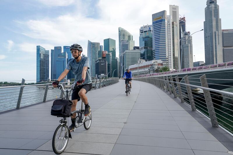 epa09134683 Two cyclists ride across the Jubilee Bridge pictured against the skyline of the financial district in Singapore, 14 April 2021. The Ministry of Trade and Industry reported that the Singapore economy grew 0.2 percent for the first quarter of 2021, an increase from the contraction of 2.4 percent recorded in the previous quarter. The manufacturing and construction industries both recorded the highest percentage increases.  EPA/WALLACE WOON
