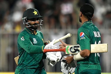 Pakistan's Shoaib Malik (R) shakes hands with teammate Asif Ali after scoring a half-century (50 runs) during the ICC men’s Twenty20 World Cup cricket match between Pakistan and Scotland at the Sharjah Cricket Stadium in Sharjah on November 7, 2021.  (Photo by Aamir QURESHI  /  AFP)