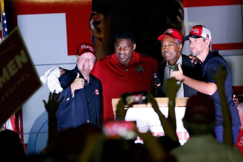 Senator Lindsay Graham, former US secretary of housing and urban development Ben Carson and radio host Clay Travis pose for a photo with Mr Walker at the end of a rally in Kennesaw. AP