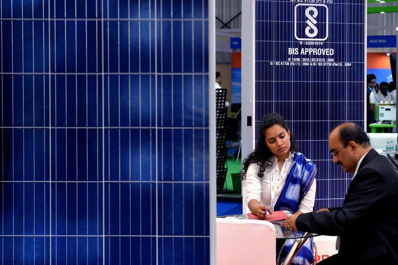 A visitor interacts with a representative next to a display of solar panels at a stall during "Inter Solar 2018", an international exhibition on solar technology and energy held in Bangalore on December 12, 2018. (Photo by MANJUNATH KIRAN / AFP)