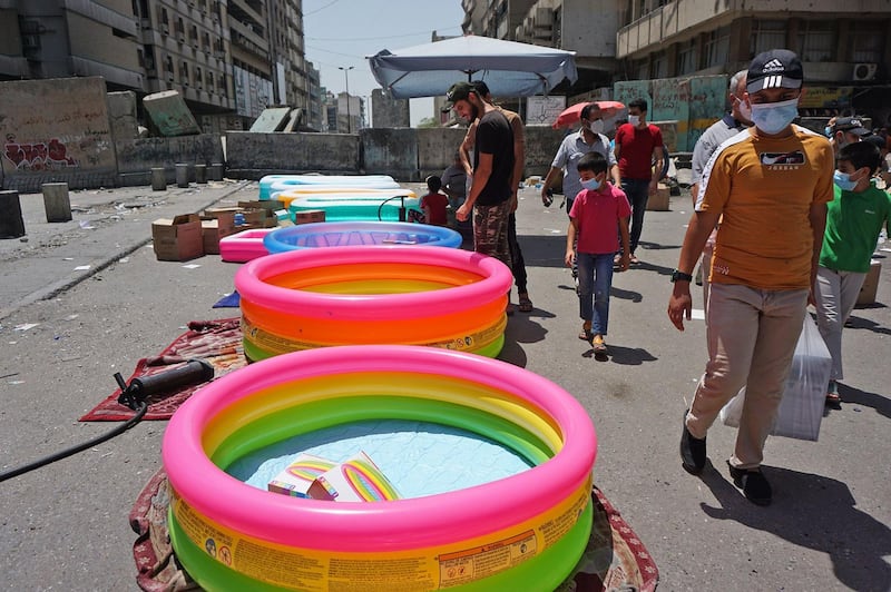 People walk past inflatable pools displayed for sale in Baghdad.  AFP