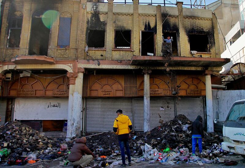 Shop owners throw out their burnt goods while cleaning their shops after clashes between security forces and anti-government protesters in Rasheed Street. AP
