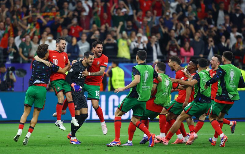 Portugal goalkeeper Diogo Costa is mobbed by teammates after saving three penalties in the shoot-out. Reuters
