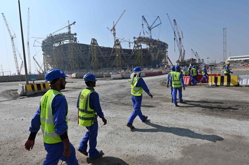 (FILES) This file photo taken on December 20, 2019 shows construction workers walking in front of Qatar's Lusail Stadium under construction, around 20 kilometres north of the capital Doha. An extraordinary congress of the Norwegian Football Federation to be held on June 20, 2021 plans to vote on a potential boycott of the upcoming World Cup in Qatar.
 / AFP / GIUSEPPE CACACE
