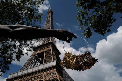 A street vendor displays miniatures of the Tour Eiffel outside of the closed Eiffel Tower in Paris, Tuesday, June 16, 2020. On June 25 the Eiffel Tower will be re-opening after the longest pause to its activity since World War II. The iconic Paris monument was closed for more than three months from March over amid the nationwide virus lockdown. (AP Photo/Francois Mori)