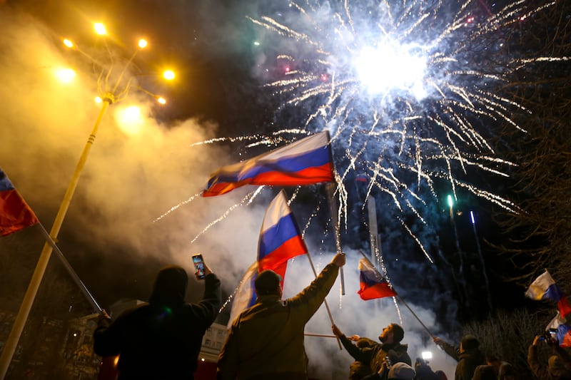 People wave Russian flags while celebrating Moscow's recognition of the self-proclaimed republic's independence, in Donetsk. AP