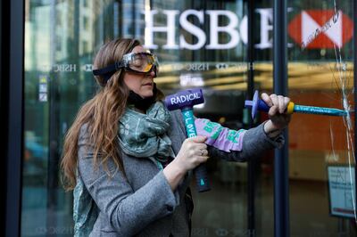 An activist from the Extinction Rebellion, a global environmental movement, smashes a window at HSBC headquarters during a protest in Canary Wharf, London, Britain April 22, 2021. REUTERS/John Sibley