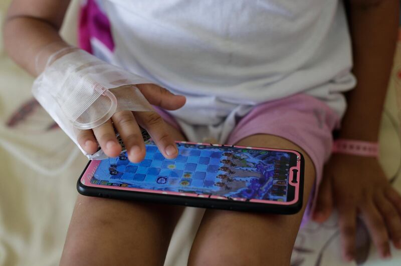 A young dengue patient plays on a smartphone at the San Lazaro government hospital in Manila. 