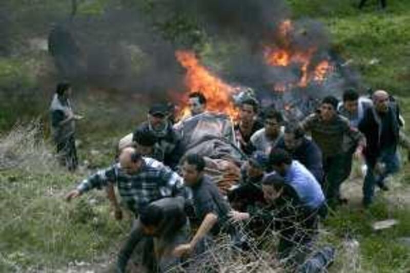 Palestinian men carry a body from a burnt car at the site of an explosion in Mieh Mieh refugee camp outside the southern Lebanese city of Sidon March 23, 2009. A roadside bomb killed Medhat and four other people in southern Lebanon on Monday, security sources said. REUTERS/Ali Hashisho    (LEBANON CONFLICT POLITICS) *** Local Caption ***  LBN05_LEBANON-EXPLO_0323_11.JPG