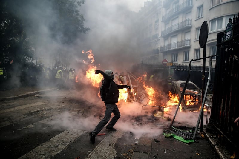 A protester throws projectile at riot police during a protest of Yellow vests in Paris. AFP