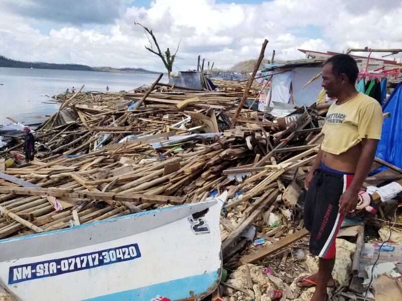 A resident looks at toppled trees and wreckage left by Typhoon Rai on Siargao Island. AP