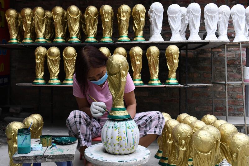 A worker paints a plaster model of the FIFA World Cup trophy at a workshop in Hanoi, in the run-up to the Qatar 2022 football tournament. AFP