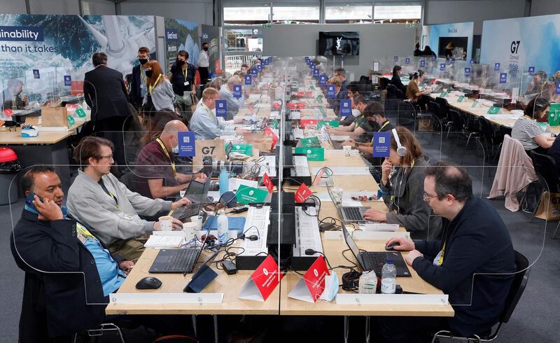 Members of the media work at desks screened-off due to Covid-19, in the media centre at Falmouth, Cornwall. AFP