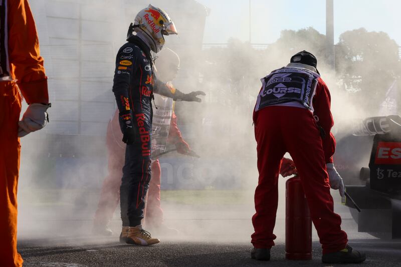 Max Verstappen gestures as a track marshal extinguishes a fire in his car. AP