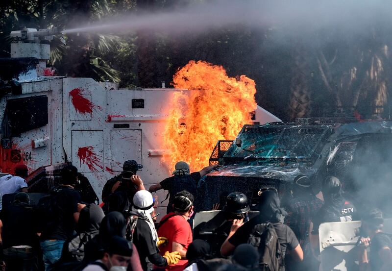 Demonstrators set a riot police vehicle on fire during clashes on the commemoration of the first anniversary of the social uprising in Chile, in Santiago.  AFP