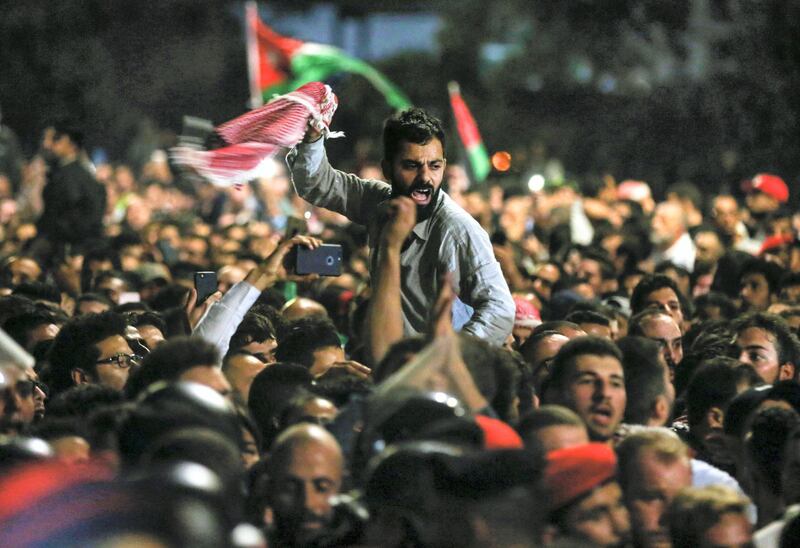 Jordanian protesters shout slogans and raise a national flag during a demonstration outside the Prime Minister's office in the capital Amman late on June 2, 2018.
Hundreds of Jordanians demonstrated in the capital Amman for a third consecutive day on June 2 against price hikes and an income tax draft law driven by IMF recommendations to slash its public debt. / AFP PHOTO / Khalil MAZRAAWI