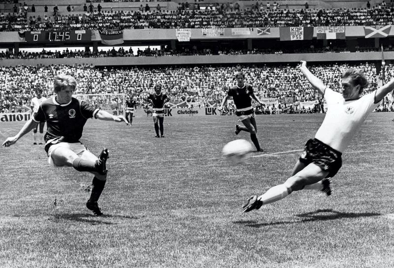 Scotland's Gordon Strachan, left, scores his team's first goal during the Football World Cup match against West Germany in Queretaro, Mexico on June 8, 1986. West German player Norbert Eder attempts to stop the shot. West Germany defeated Scotland 2-1. (AP Photo/Staff/Kienzle)