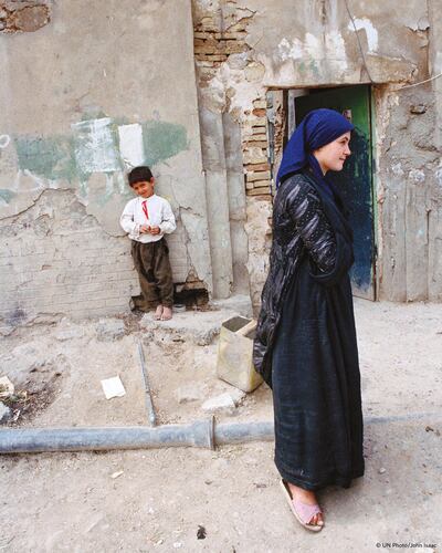 A Kurdish family stand outside a damaged home in Erbil, northern Iraq in 1991. Courtesy UN