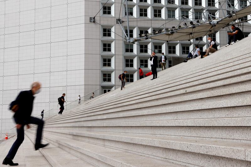 FILE PHOTO: People wearing protective face masks walk at the financial and business district of La Defense in Nanterre as work rules have been relaxed with working-from-home requirements gradually being lifted amid the coronavirus disease (COVID-19) outbreak in France, June 10, 2021.  REUTERS/Pascal Rossignol/File Photo