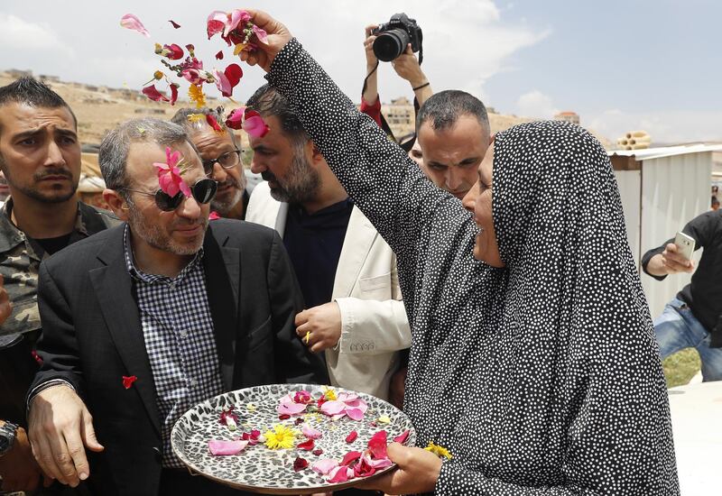 A Syrian refugee woman throws flowers on Lebanese Foreign Minister Gibran Bassil, center, during his visit a Syrian refugee camp, in Arsal, near the border with Syria, east Lebanon, Wednesday, June 13, 2018. A public spat between the Lebanese government and the United Nation's refugee agency deepened Wednesday as Lebanon's caretaker foreign minister kept up his criticism, accusing the agency of discouraging Syrian refugees from returning home. Lebanon is home to more than a million Syrian refugees, or about a quarter of the country's population, putting a huge strain on the economy. (AP Photo/Hussein Malla)
