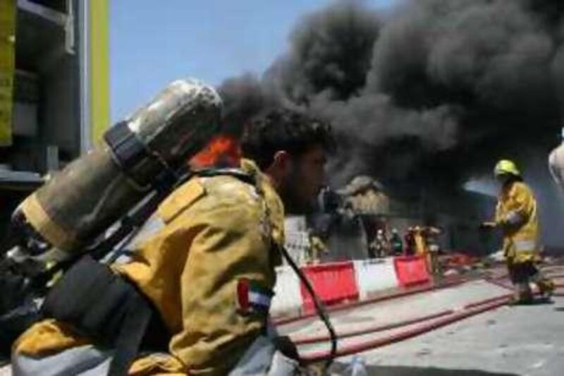 DUBAI - APRIL 4, 2008 -  A fire fighter rest after getting exhausted on the thick smoke  from a burning warehouse in Al Quoz, Thursday morning. ( Paulo Vecina / The National ) *** Local Caption *** NA06-PaintFire1.jpg